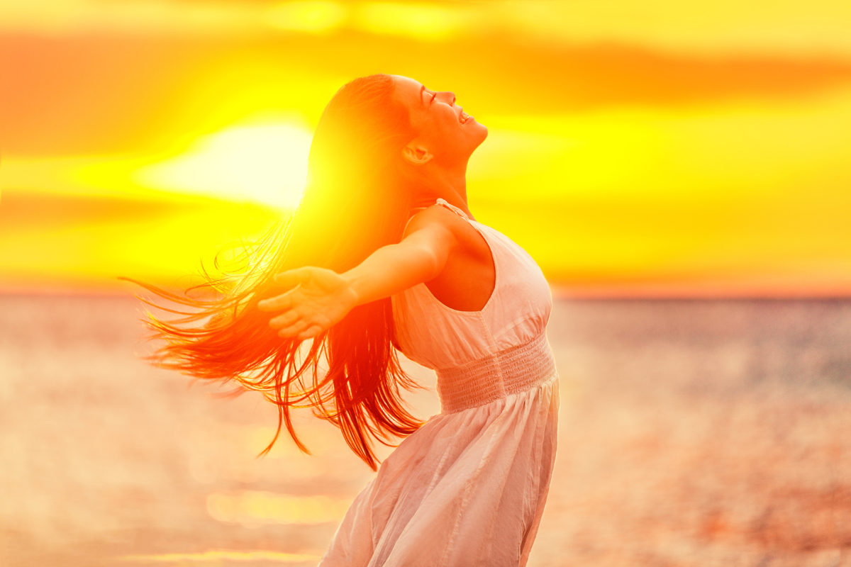 Happy woman feeling free with open arms in sunshine at beach sun Happy woman feeling free with open arms in sunshine at beach sunset. Freedom and carefree enjoyment girl enjoying life. Beautiful woman in white dress for success, health, hope and faith concept.
